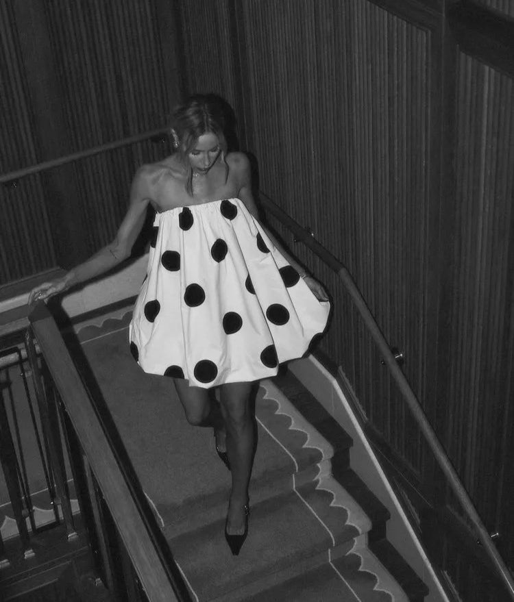Woman in a polka dot dress walking down a staircase