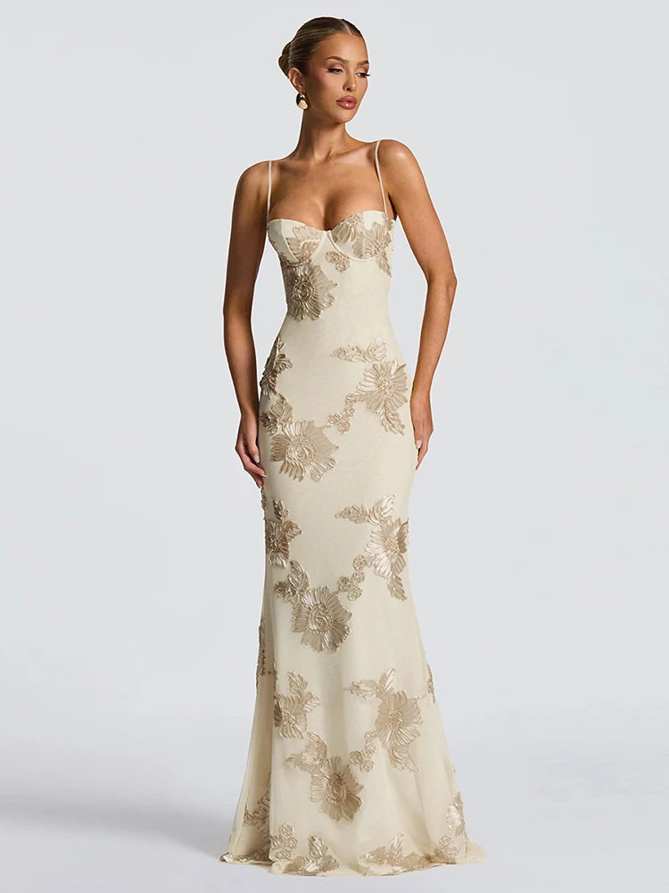 Woman wearing a strapless evening gown with floral lace details on a plain background