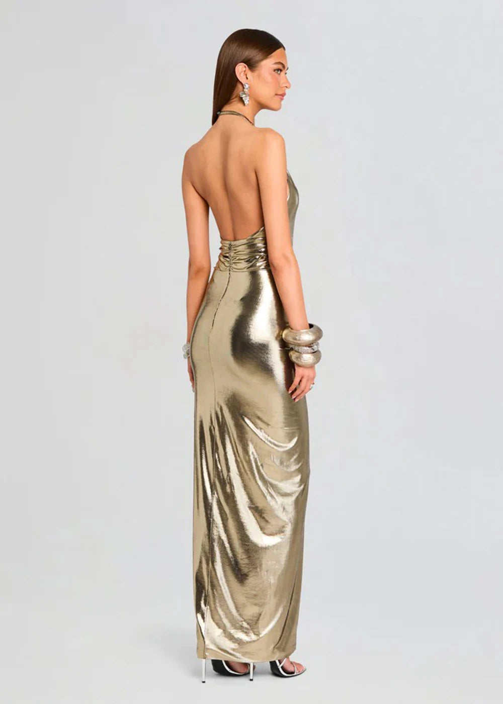 Woman wearing a gold metallic dress on a light gray background