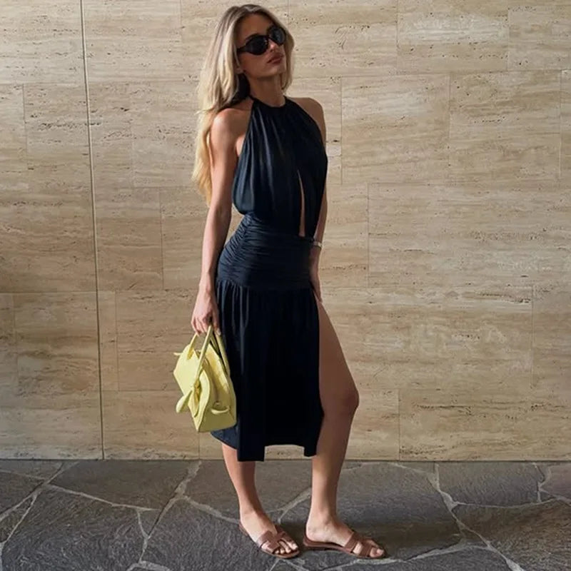 Woman in a black dress holding a yellow bag against a beige wall.