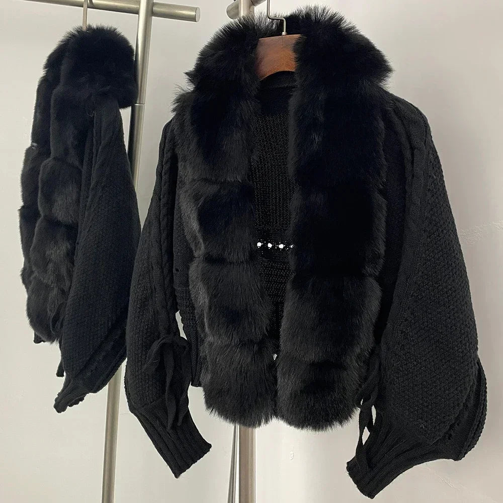Black knit cardigan with fur trim on a hanger against a neutral background