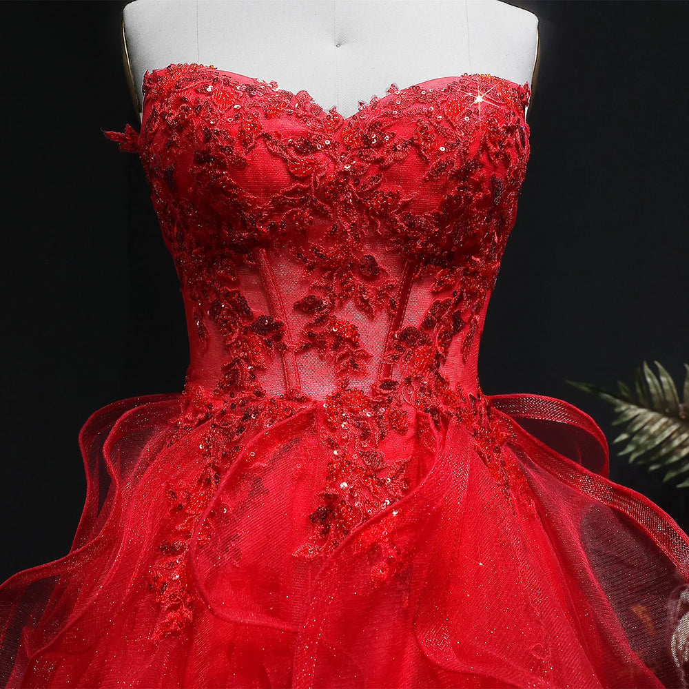 Red evening gown with floral embellishments on a mannequin against a dark background