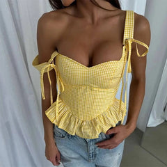 Yellow checkered top worn by a person against a white curtain background