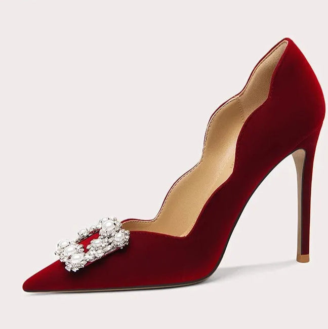 Red high-heeled shoe with decorative bow on a light gray background