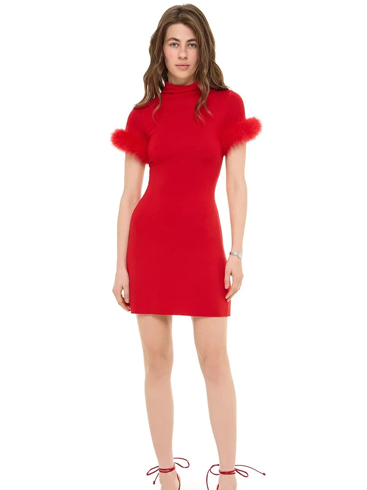 Red dress with feathered shoulders worn by a model on a white background