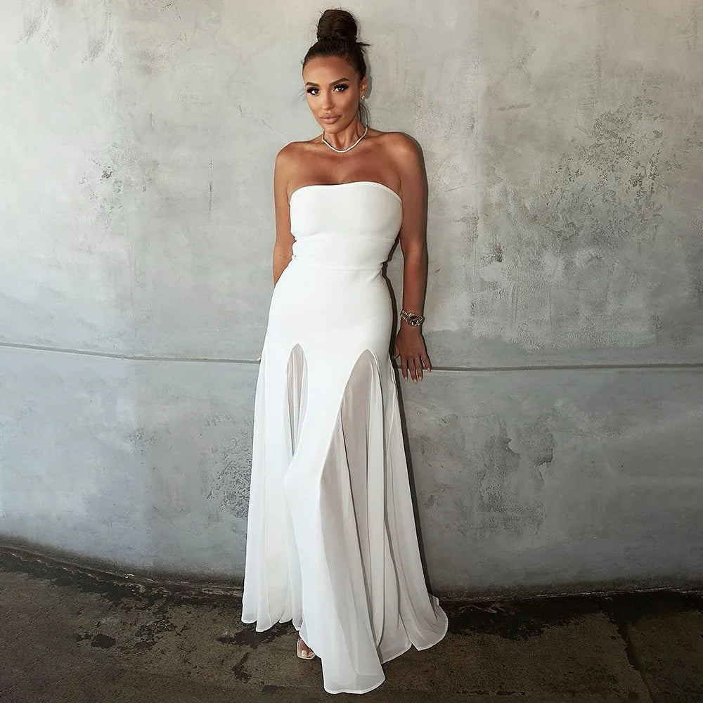 Woman in a strapless white dress standing against a textured wall.