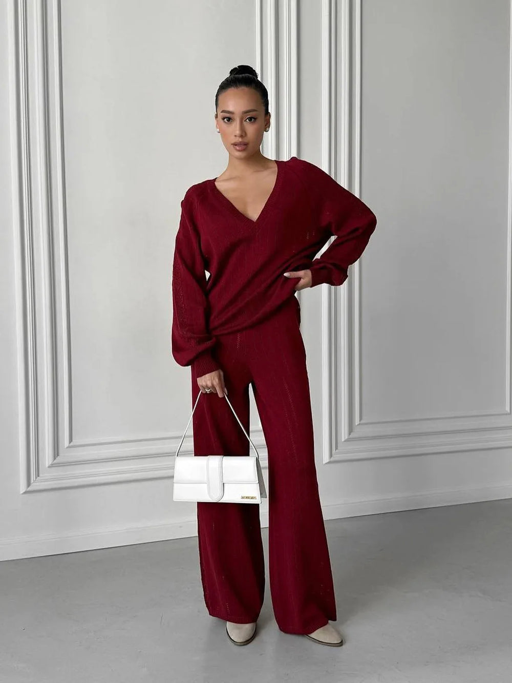 Woman wearing a burgundy outfit with a white wall background