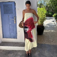 Woman holding a strapless dress with a colorful design in front of a blue door.