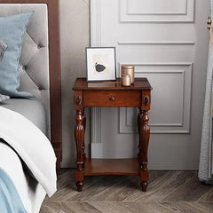 Wooden nightstand with decorative items next to a bed in a bedroom setting.