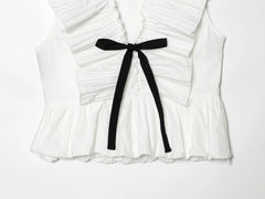 Close-up of the bow tie and pleated details on a white sleeveless peplum top.