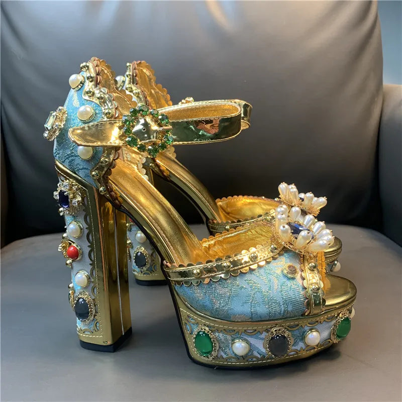 Decorative high-heeled shoes with gold, blue, and pearl details on a gray surface.