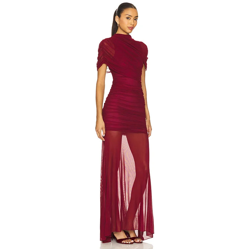 Woman wearing a burgundy evening gown with sheer panels on a white background