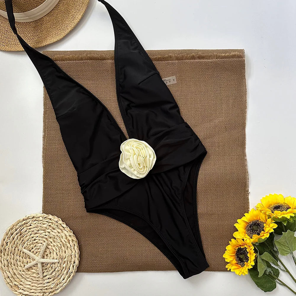Flat lay of a black one-piece swimsuit with rosette detail