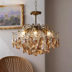 Gold chandelier with crystal accents hanging in a room with a painting and chair.