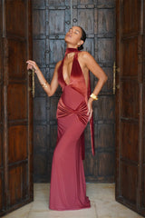 Woman in a red evening gown standing in front of a large wooden door.