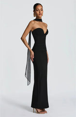 Woman wearing a black strapless gown with a sheer overlay on a white background
