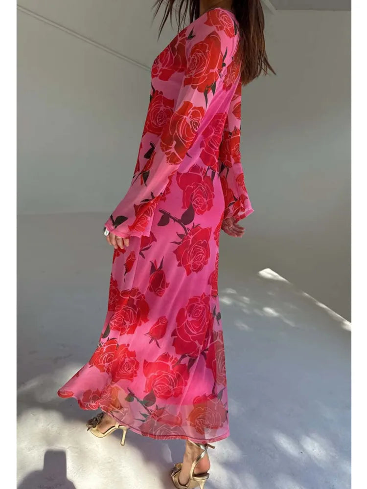 Person wearing a pink floral dress with red flowers in a minimal indoor setting