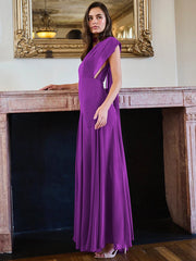 Woman in a purple evening gown standing in front of a fireplace.