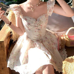 Woman wearing a romantic floral prairie mini dress with flying sleeves and V-neck, sitting in summer sunlight