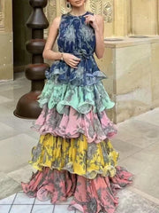 Woman wearing a colorful, layered dress with floral patterns in an indoor setting.