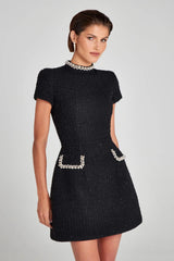 Black dress with embellishments on a gray background