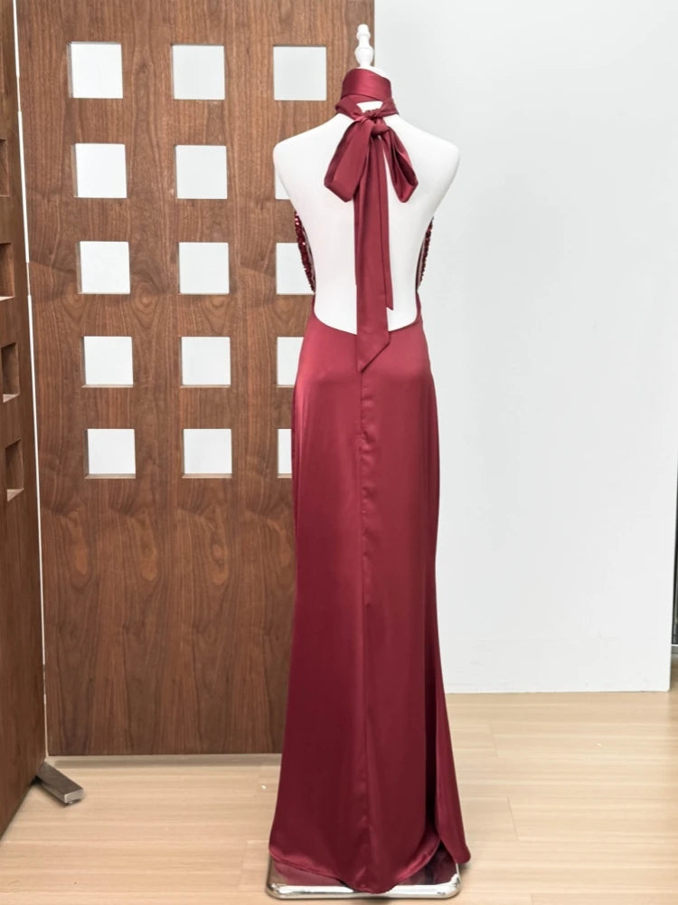 Maroon evening gown on a mannequin against a wooden panel background