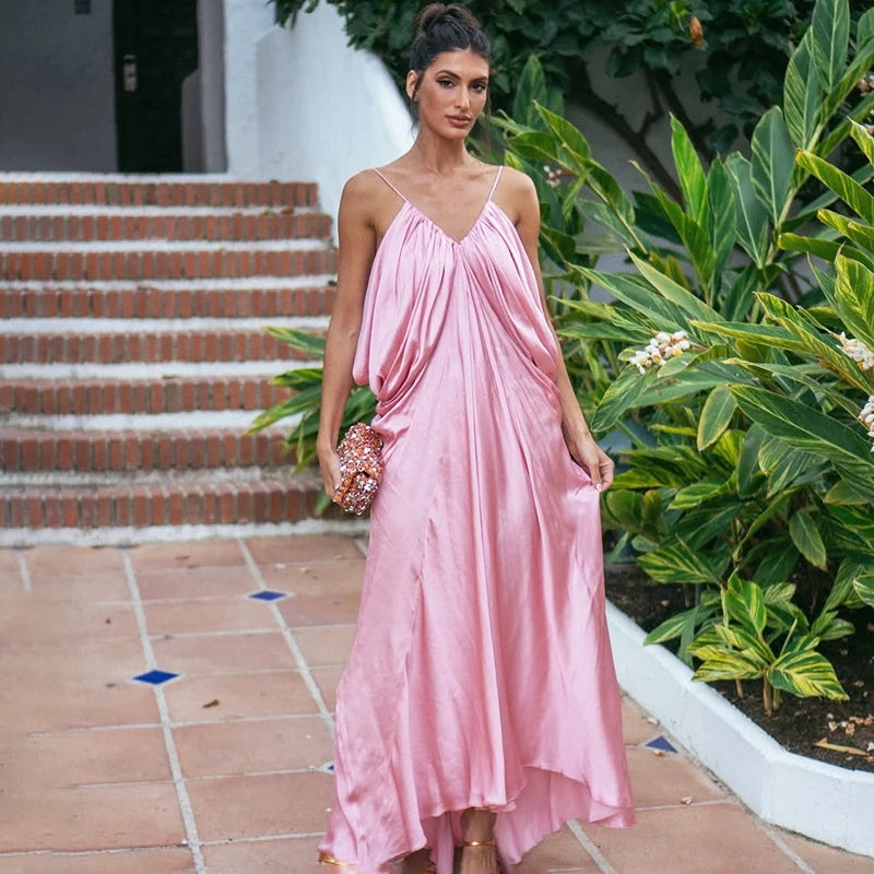 Woman in a pink dress standing outdoors with greenery and steps in the background