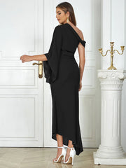 Woman in a black off-shoulder dress standing in a elegant interior setting.