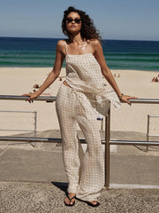 Woman in a polka dot dress standing on a beach with ocean view