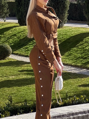 Woman in a brown outfit standing outdoors on a grassy area.
