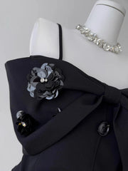 Black coat with floral brooch and silver bracelet on a mannequin against a gray background