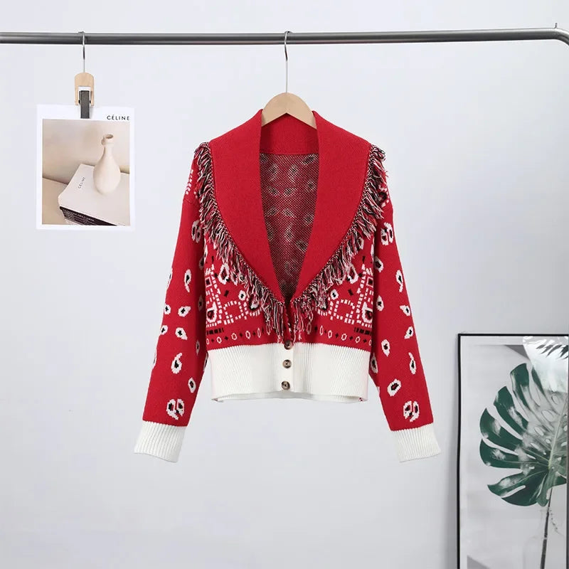 Red patterned cardigan on a hanger against a light gray background