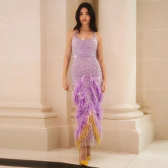 Woman wearing a purple beaded evening gown with feather details in an elegant setting.