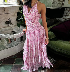 Woman in a pink floral dress standing in a room with a stone wall and green sofa.