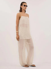 Woman wearing a white polka dot outfit on a plain background