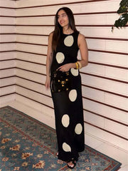 Woman wearing a black dress with white polka dots in an indoor setting.