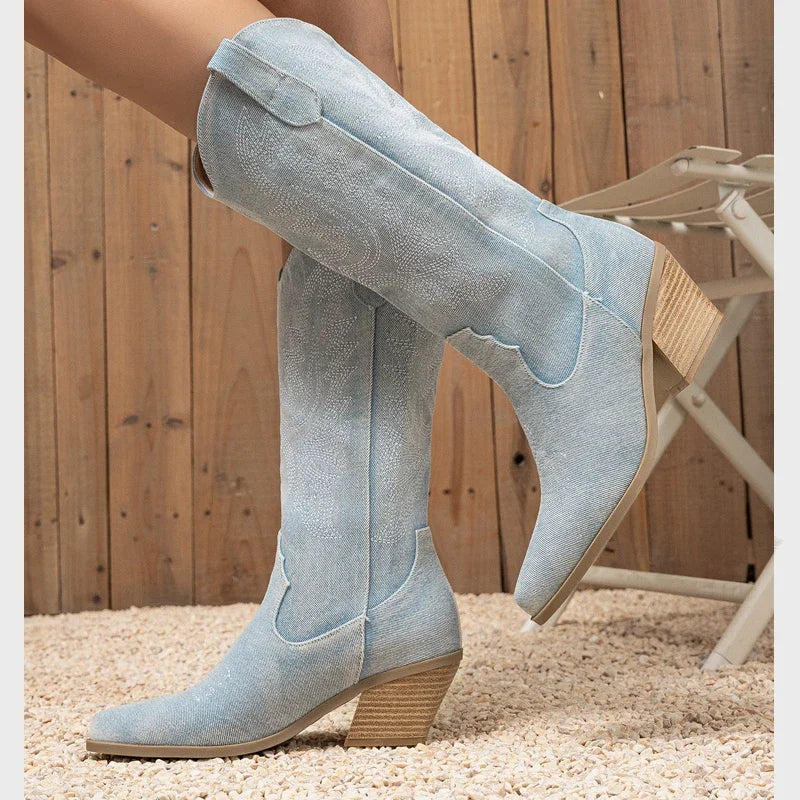 Light blue suede boots with brown soles worn by a person sitting on a wooden deck.
