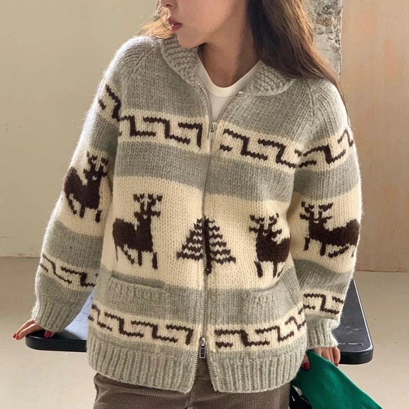 Person wearing a gray knitted cardigan with deer and tree pattern