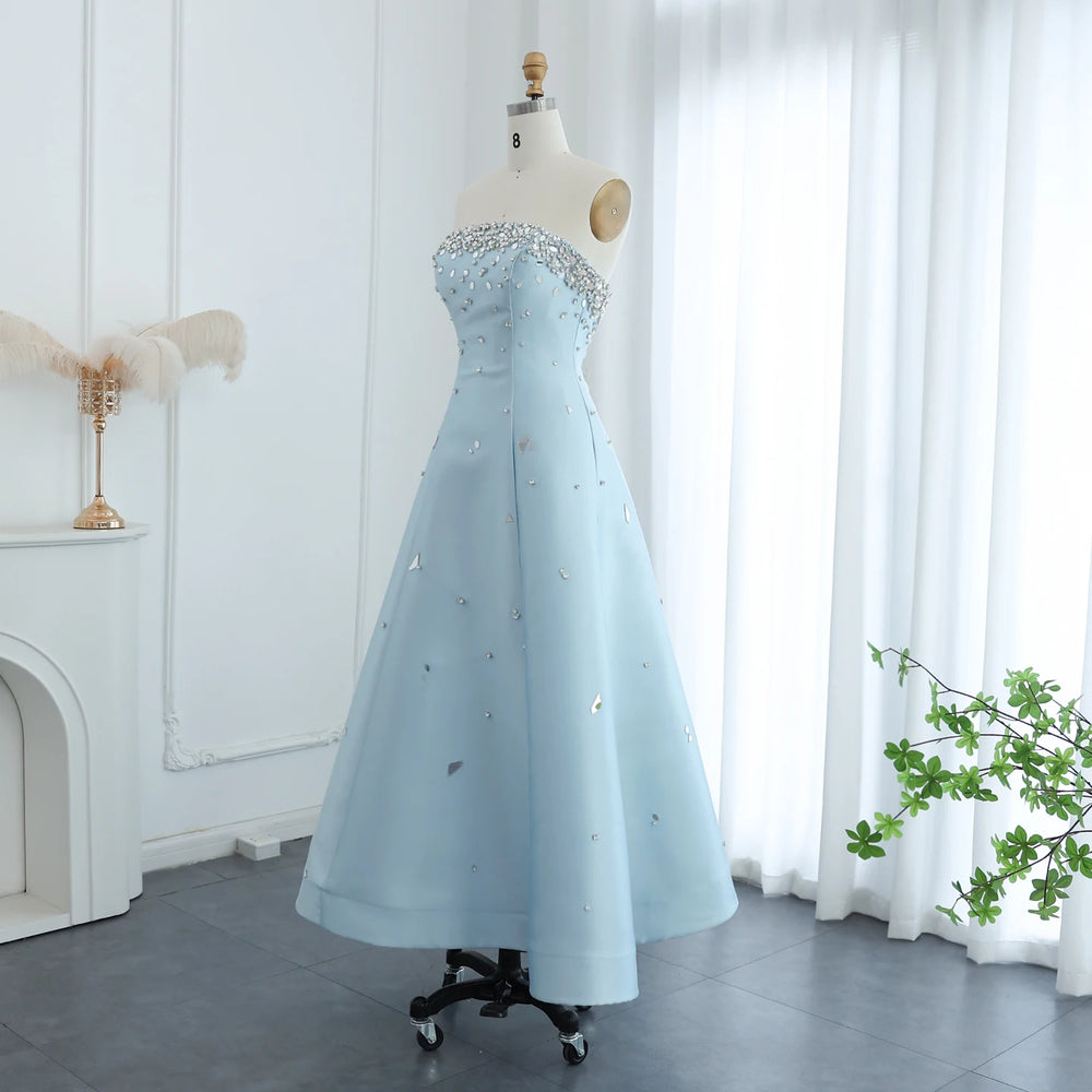 Light blue evening gown on a mannequin in a room with white curtains and a fireplace.