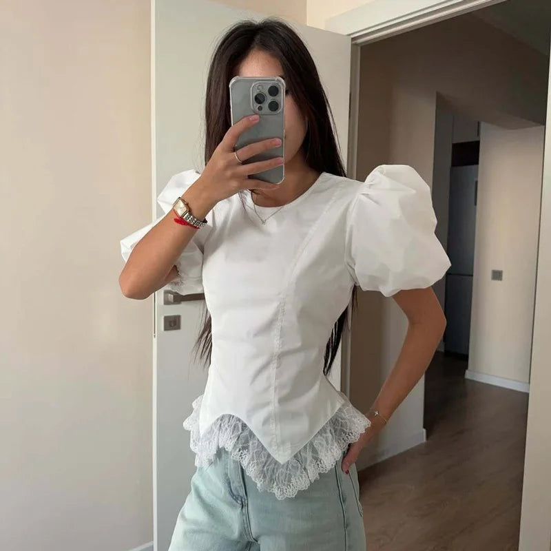 Person wearing a white blouse with puffed sleeves and lace details, taking a mirror selfie.