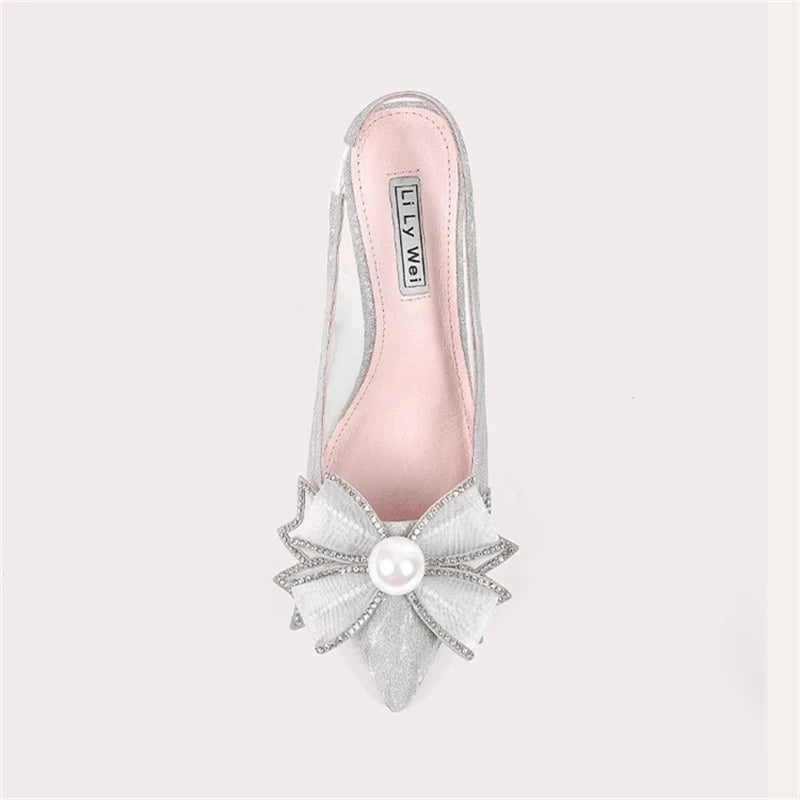 Silver sandal with decorative bow and pearl on a light gray background