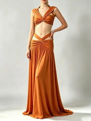 Model wearing an orange halter neck ruched crop top and cutout maxi skirt