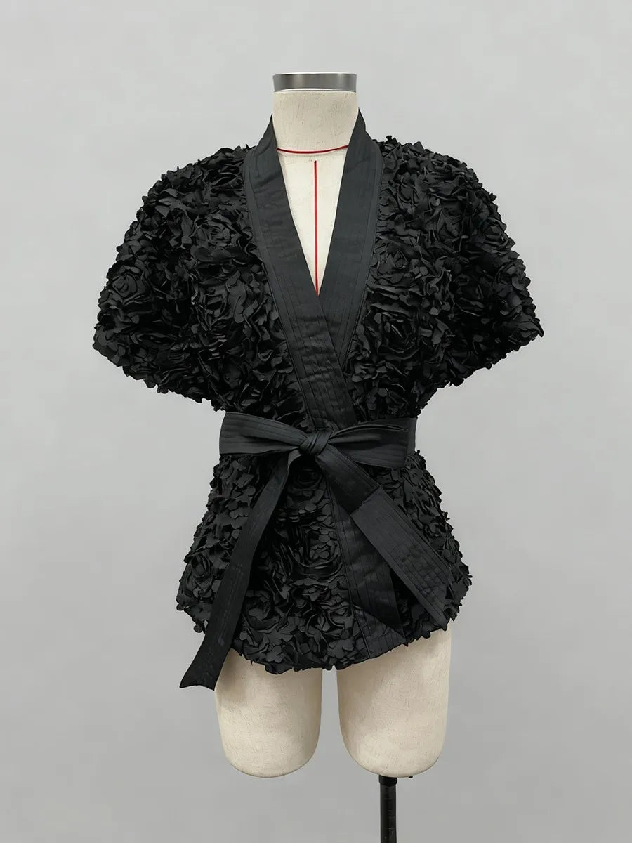 Black floral-patterned top with a belt on a mannequin against a gray background