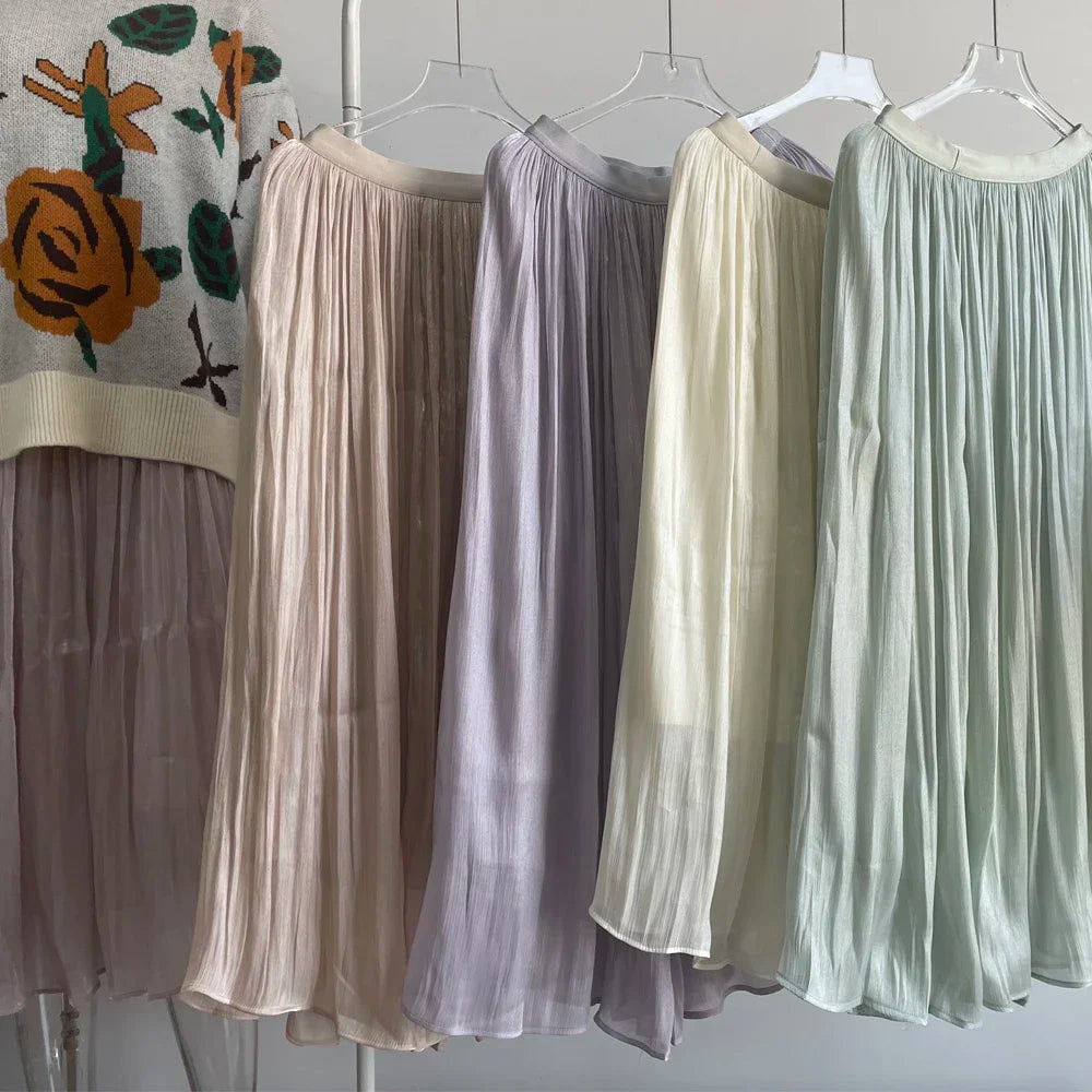 Four sheer skirts in different colors hanging on a rack against a tiled wall.