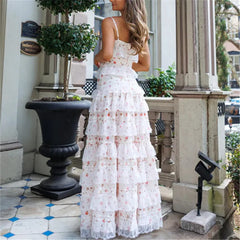 Woman in a white floral dress standing on a porch.