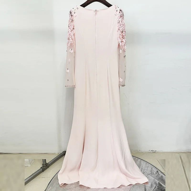 Pink dress with floral embellishments on a hanger against a white background