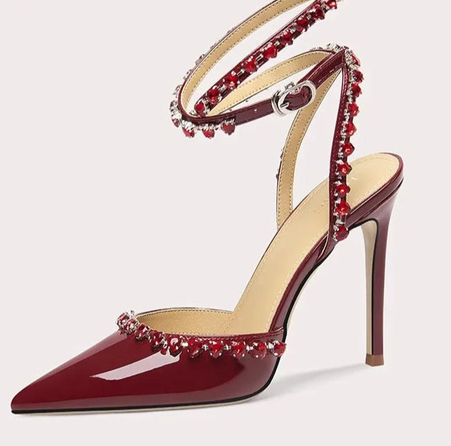 Red high-heeled shoe with decorative straps on a white background