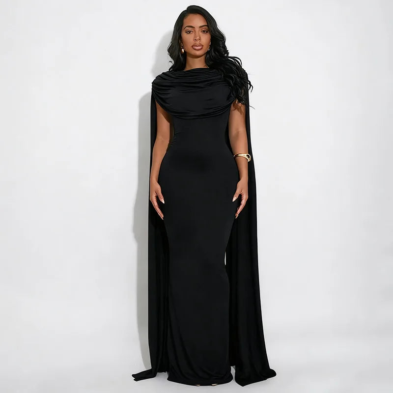 Woman wearing a black evening gown with a cape on a white background