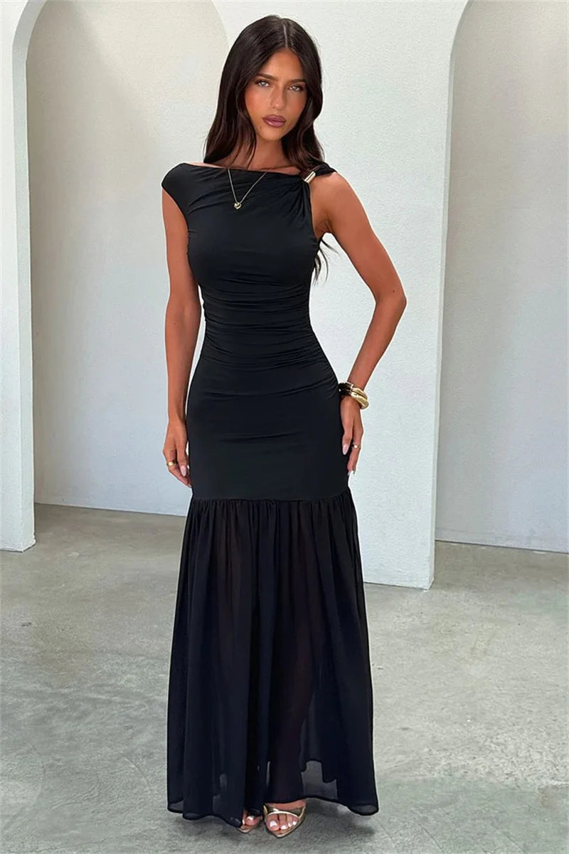 Woman wearing a black dress standing against a white wall.