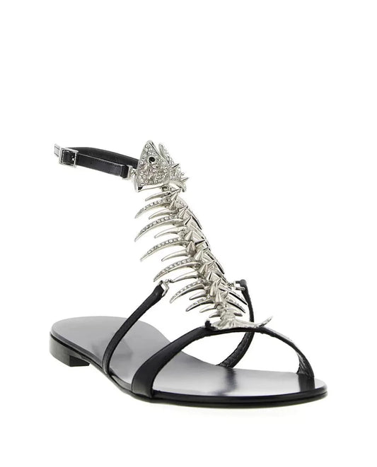 Black flat sandal with a silver rhinestone fishbone embellishment and ankle strap